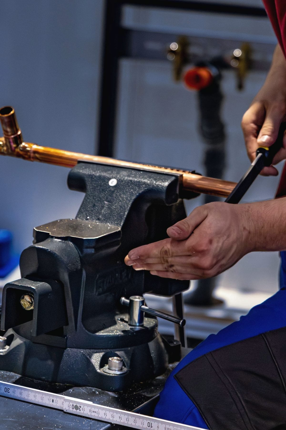 Hands bending a length of copper tube clamped in a bench vise