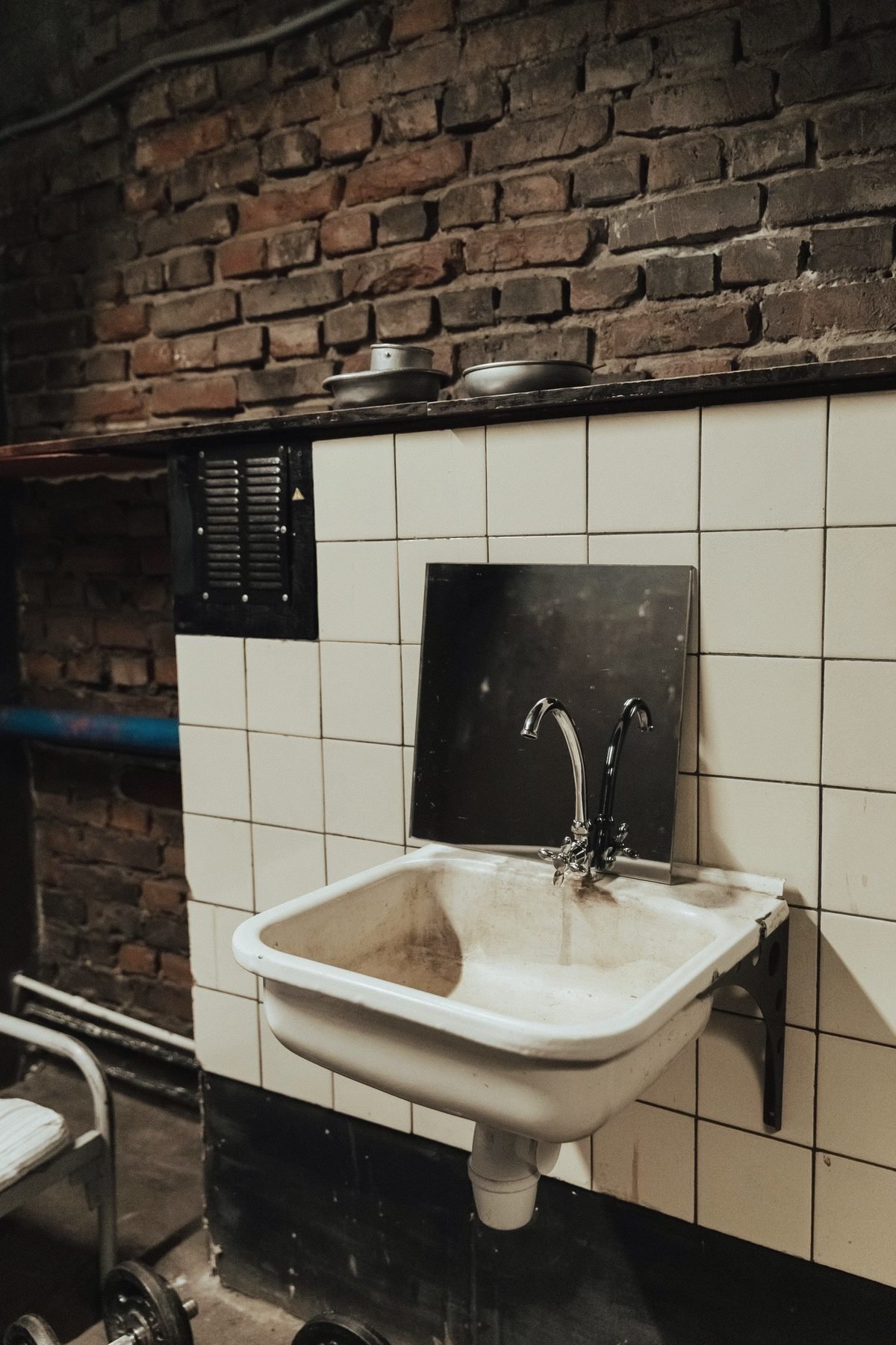 A white utility sink mounted on a painted brick basement wall